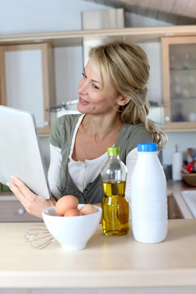 Mujer en la cocina mirando la receta de postre en internet — Foto de Stock