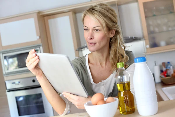 Mujer en la cocina mirando la receta de postre en internet —  Fotos de Stock