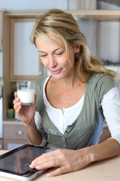 Retrato de mujer rubia bebiendo leche en la cocina casera — Foto de Stock