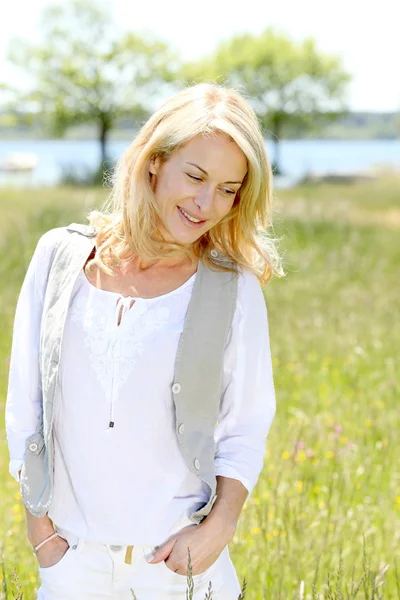 Beautiful woman standing in country field in summer time — Stock Photo, Image