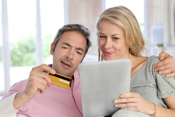 Casal sentado no sofá em casa e fazendo compras on-line — Fotografia de Stock