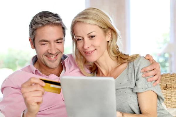 Casal sentado no sofá em casa e fazendo compras on-line — Fotografia de Stock