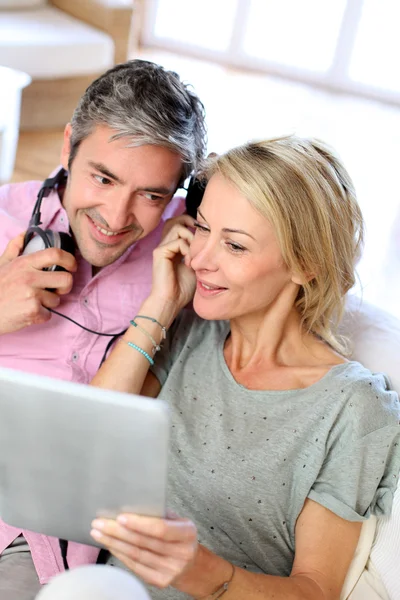 Пара слухає музику вдома з планшетом — стокове фото