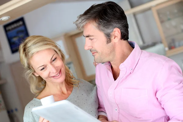 Middle aged couple using tablet in kitchen — Stock Photo, Image