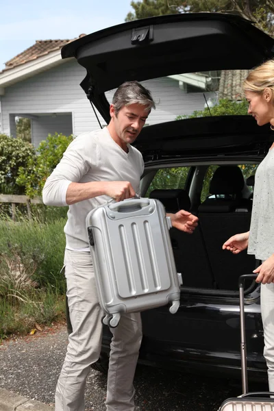 Couple putting suitcases in car trunk for a journey — Stock Photo, Image