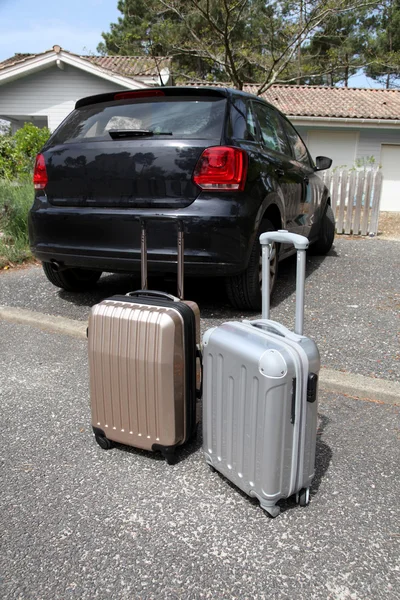 Closeup of suitcases set by a car in driveway — Stock Photo, Image