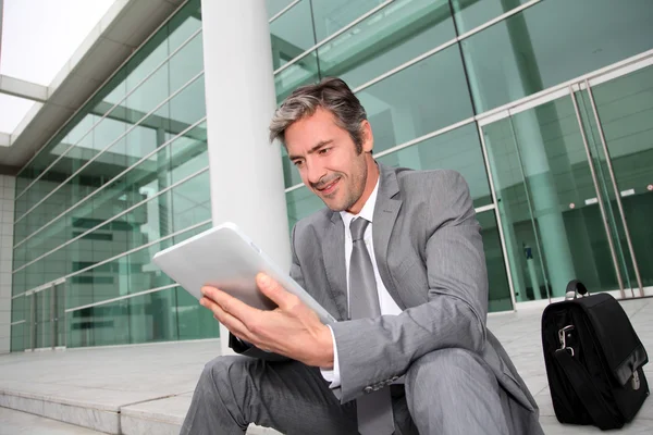 オフィスビルの前で電子タブレットを使うビジネスマン — ストック写真