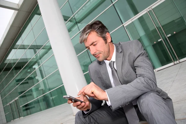 Geschäftsmann benutzt Handy im Sitzen im Treppenhaus — Stockfoto