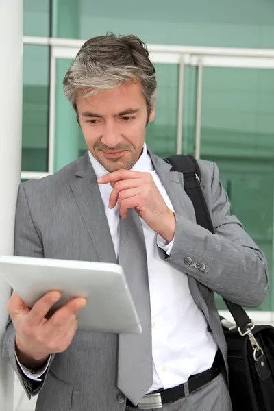 Бізнесмен стоїть зовні будівлі з електронним планшетом — стокове фото