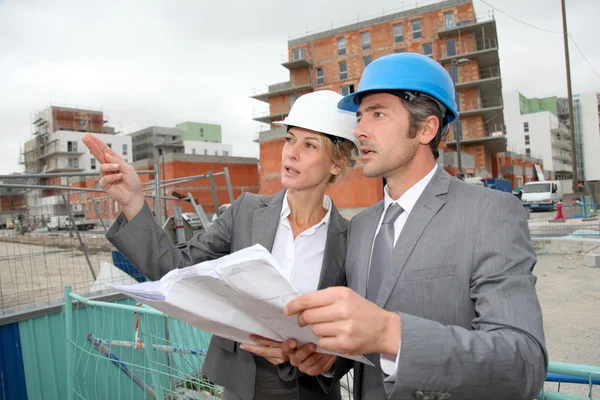 Construction engineers checking plan on building site — Stock Photo, Image