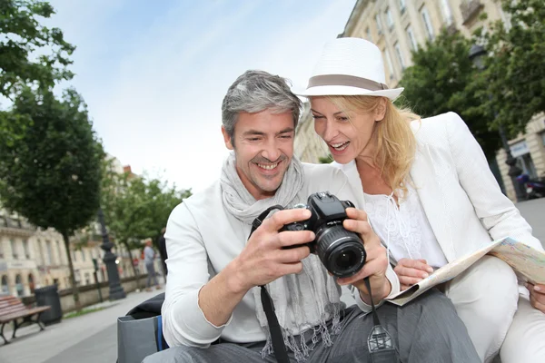 Turistas felizes olhando para fotos na tela da câmera — Fotografia de Stock