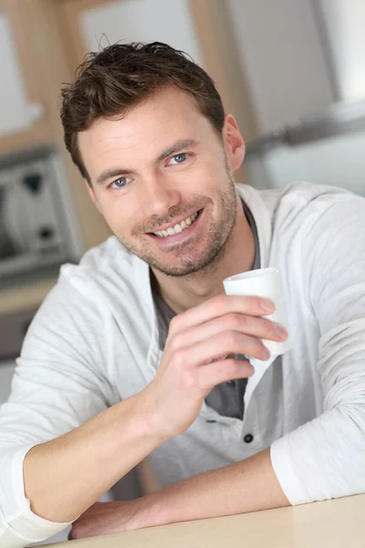 Portrait of handsome guy drinking coffee in home kitchen Stock Photo