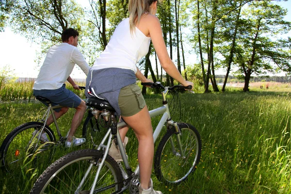 Coppia biciclette a cavallo in campo in riva al lago Fotografia Stock