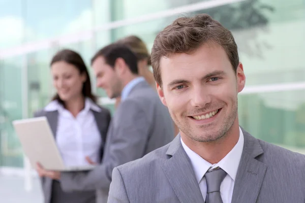 Hombre de negocios guapo de pie frente al grupo de Fotos de stock libres de derechos