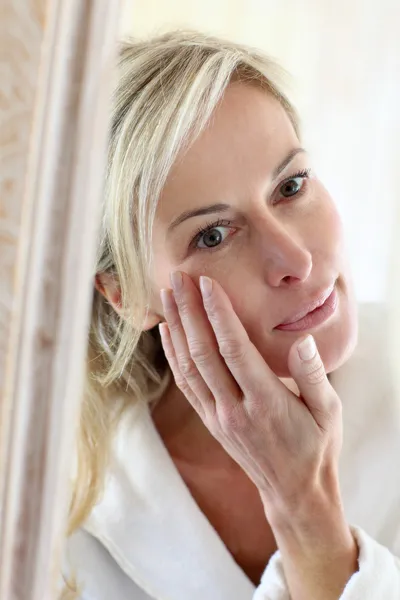Attractive middle-aged woman applying comestics on her face Stock Photo