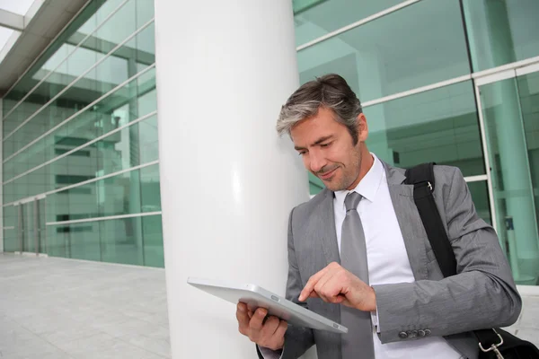 Businessman standing outside building with electronic tablet Stock Photo