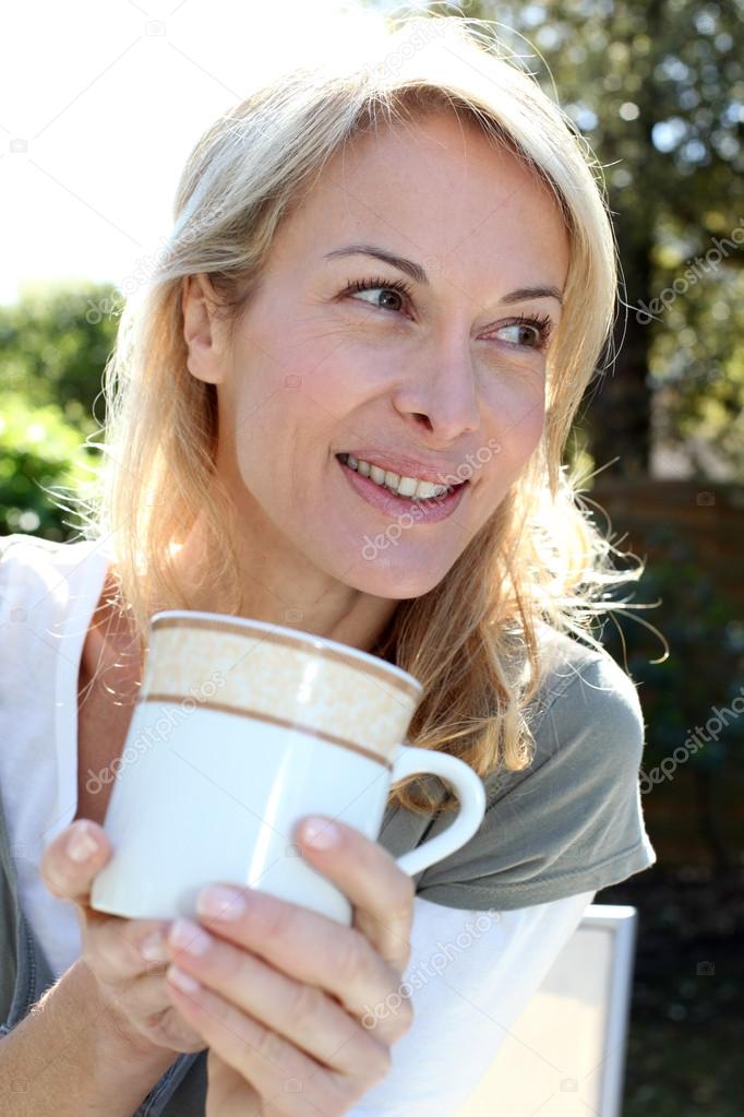 Portrait of blond woman with tea mug sitting outside