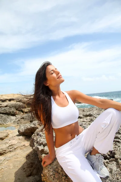 Mujer sentada en las rocas en traje de fitness —  Fotos de Stock