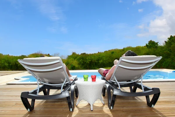Back view of relaxing on pool deck chairs — Stock Photo, Image