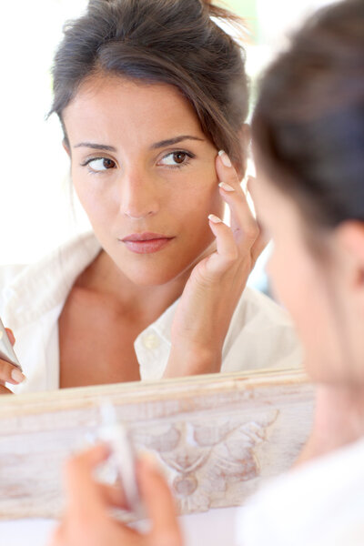 Portrait of beautiful woman applying anti-wrinkles cream