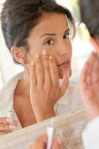 Portrait of beautiful woman applying anti-wrinkles cream