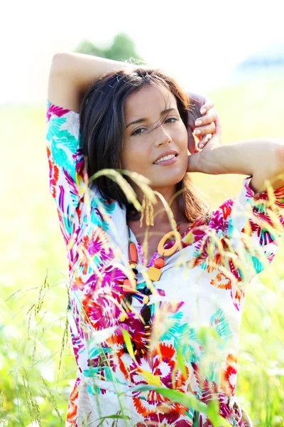 Brunette tyttö värikäs paita seisoo niitty — kuvapankkivalokuva