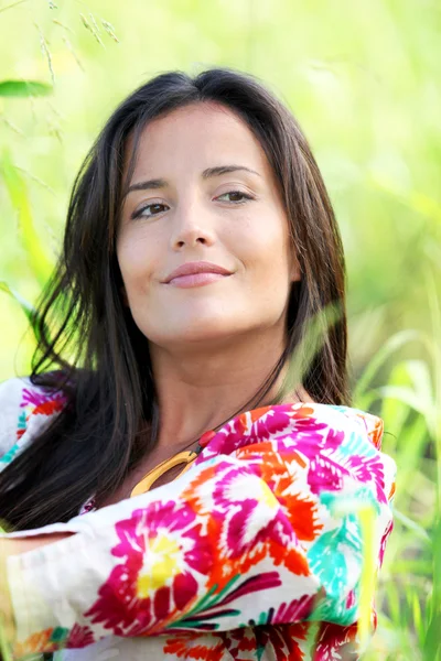 Closeup of beautiful brunette girl sitting in meadow — Stock Photo, Image