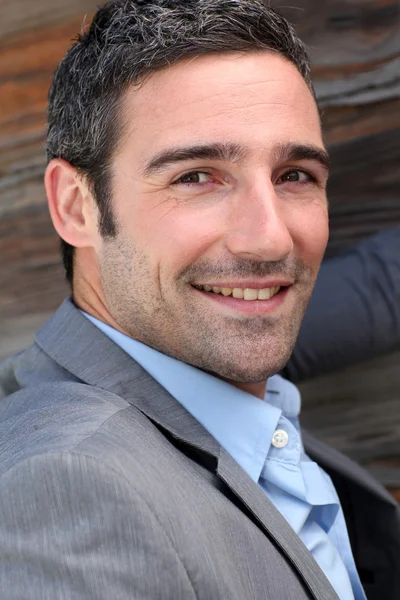 Portrait of businessman standing in front of wooden wall — Stock Photo, Image