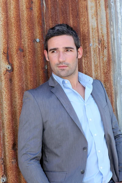 Businessman standing in front of sheet metal wall — Stock Photo, Image