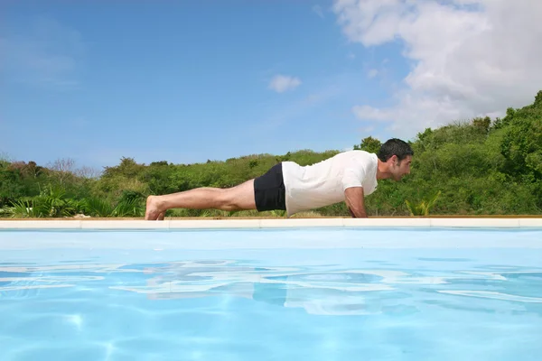 Hombre haciendo ejercicios junto a la piscina — Foto de Stock