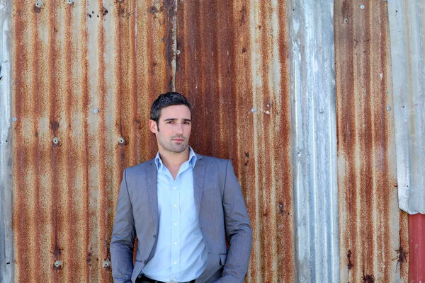 Empresário em pé na frente da parede de chapa metálica — Fotografia de Stock