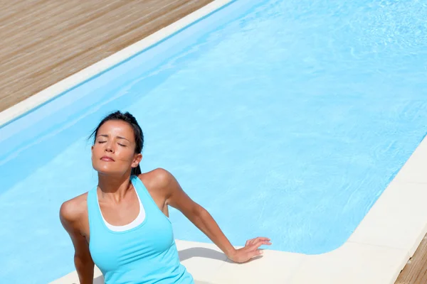 Brunette girl in fitness outfit relaxing by the pool Stock Photo