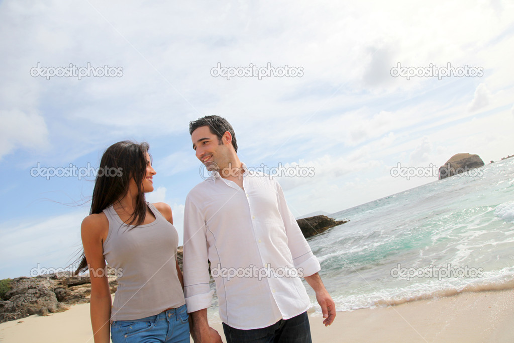 Happy couple walking by caribbean beach