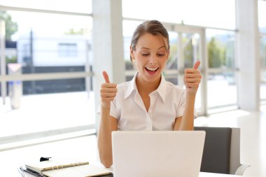 neşeli ofis çalışanı gösteren başparmak yukarıya laptop önünde