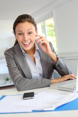 masasında oturan gülümseyen iş kadını