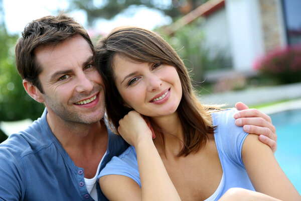 Cheerful couple sitting in front of new house