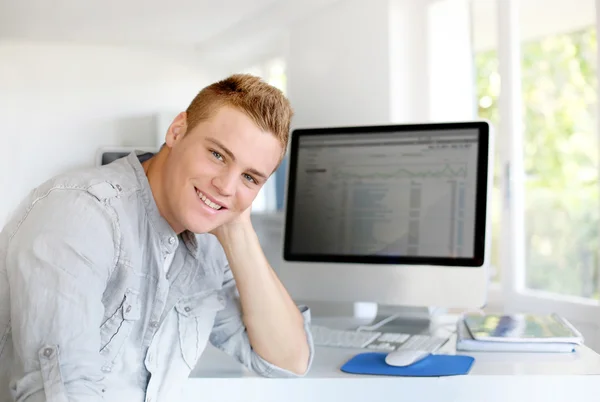 Portrait of young man sitting in front of computer — Stock Photo, Image