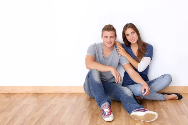 Couple of teenagers sitting against white wall — Stock Photo, Image