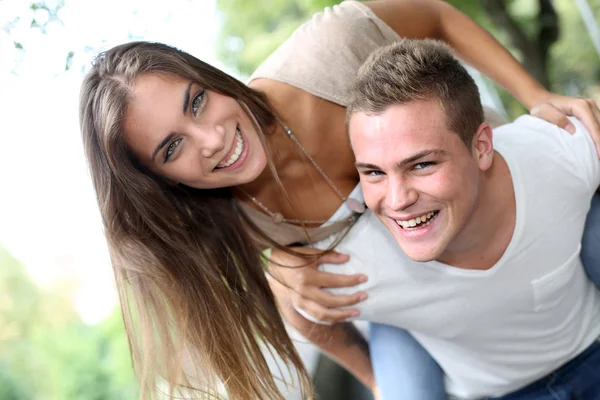 Young man carrying girlfriend on his back — Stock Photo, Image