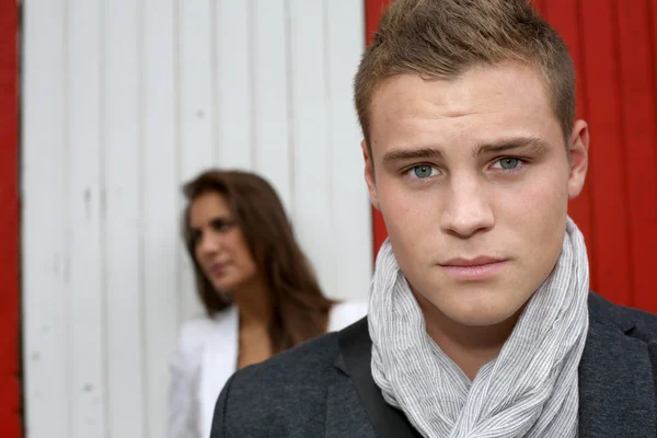 Portrait of young man with girl in background — Stock Photo, Image