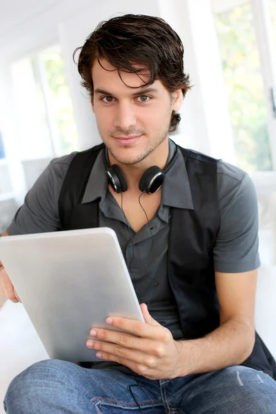 Schöner Kerl, der mit dem Tablet Musik im Internet hört — Stockfoto