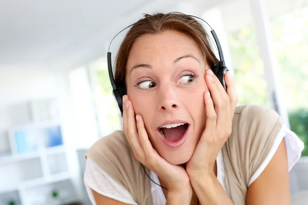 Веселая молодая женщина слушает музыку в наушниках — стоковое фото