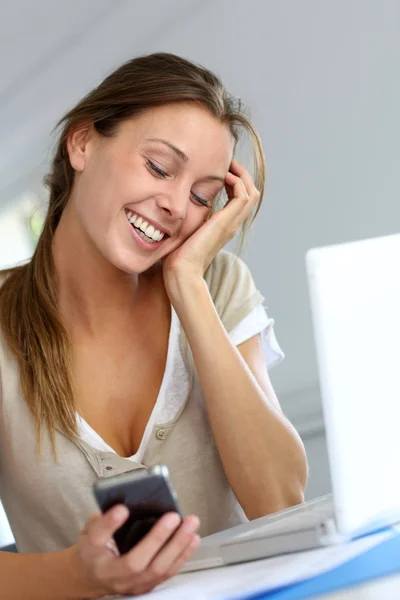 Молодая женщина с удовольствием читает сообщения по телефону — стоковое фото