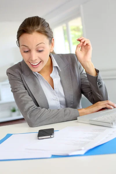 Mujer de negocios sonriente sentada en su escritorio —  Fotos de Stock