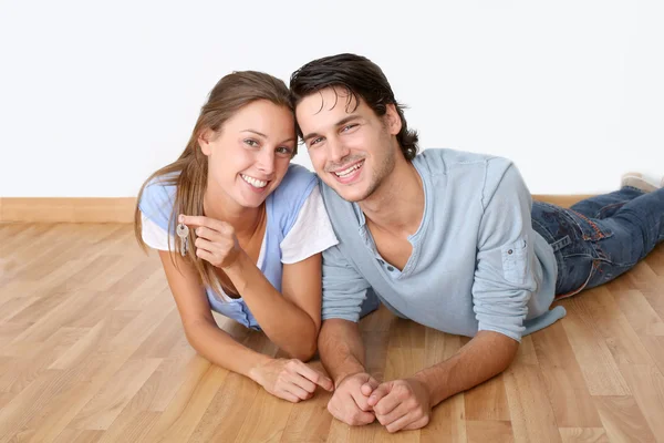 Cheerful couple laying down wooden floor — Stock Photo, Image