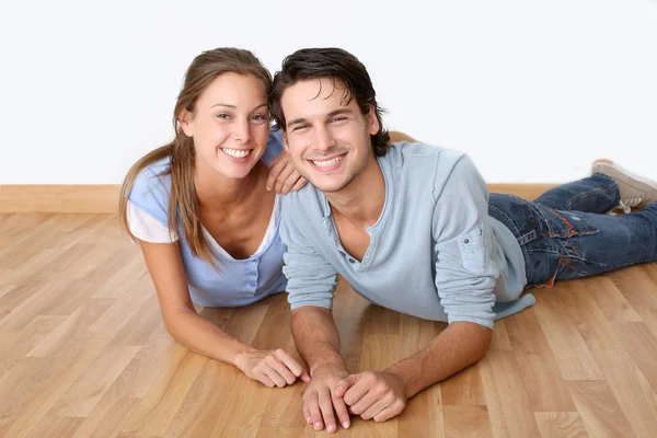 Alegre pareja acostada piso de madera — Foto de Stock