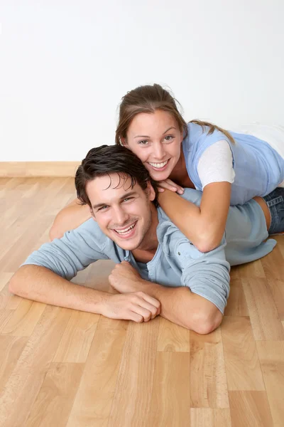 Cheerful couple laying down wooden floor — Stock Photo, Image