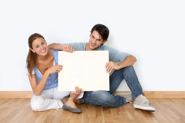 Casal sentado no chão com quadro de mensagens — Fotografia de Stock