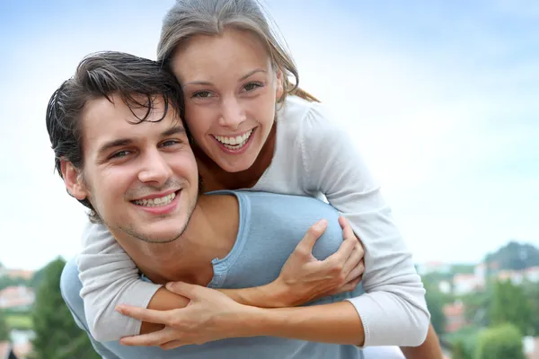 Homem dando piggyback passeio para namorada fora — Fotografia de Stock