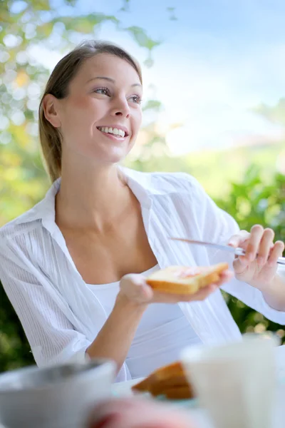 Ung kvinna med bröd till frukost — Stockfoto